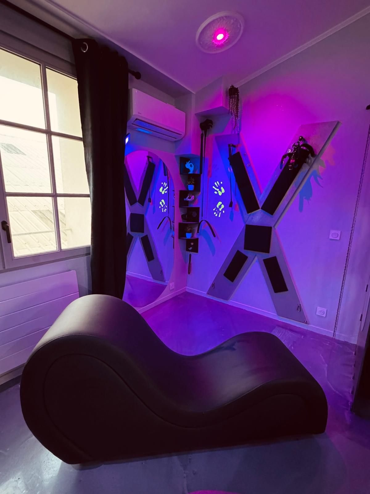 Una habitación con sillón de masajes, ventilador de techo y ventana con cortinas.