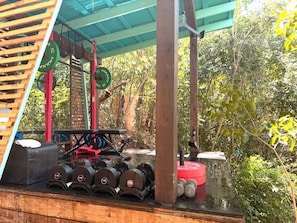 A covered outdoor gym area with weightlifting equipment, including barbells, weight plates, and a bench. - Cocoa Tea Villa (Coral Bay)