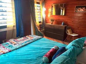 A room with a bed, a dresser, a chair, and a mirror on the wall. - Cocoa Tea Villa (Coral Bay)