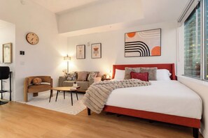 Habitació d'hotel moderna amb un llit gran, un sofà, una taula de cafè i un escriptori.