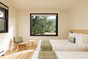Ein Schlafzimmer mit großem Fenster, einem Bett, einem Sessel und einem kleinen Hocker.