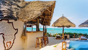A beachside resort with thatched umbrellas, a pool, and a sign with a heart-shaped outline. - Jua Boutique Hotel (Jambiani)