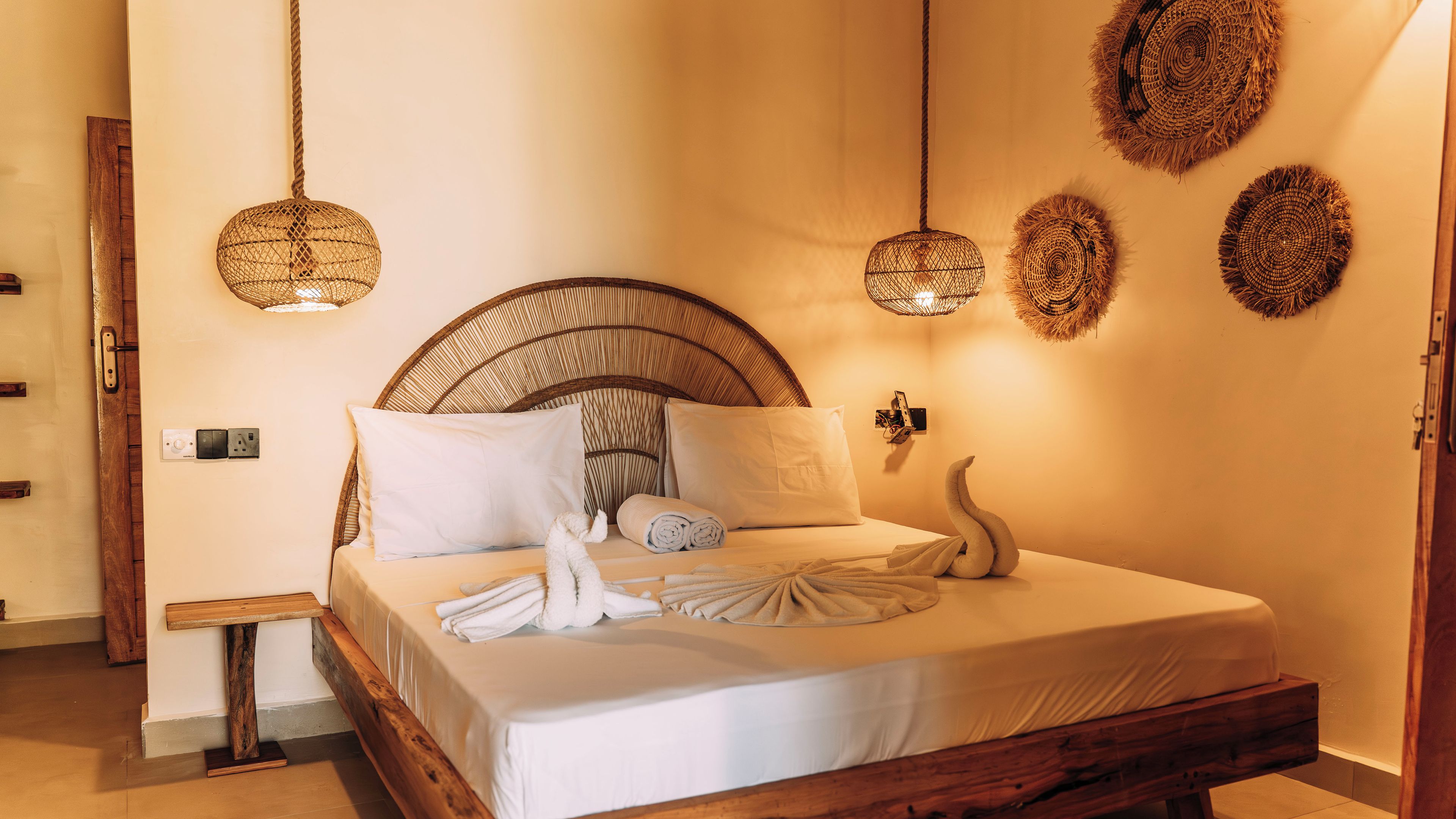 A neatly made bed with white linens, a wooden headboard, and a decorative swan pillow.