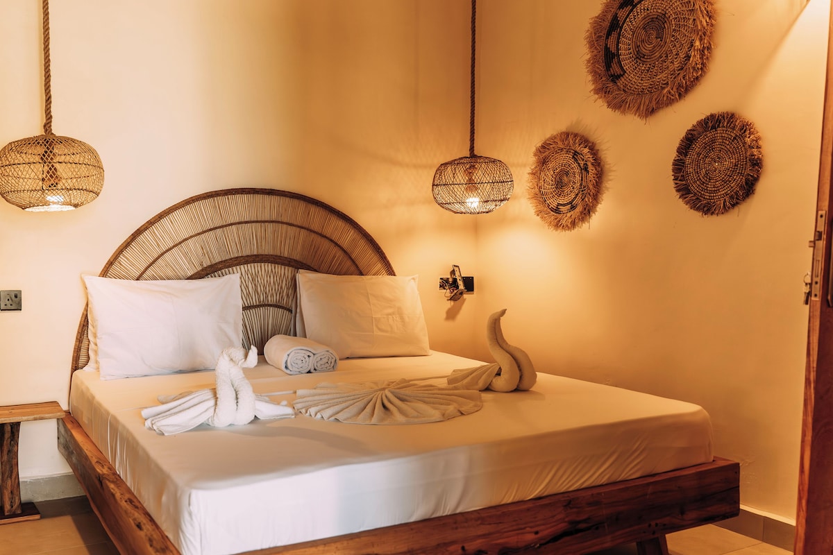 A neatly made bed with white linens, a wooden headboard, and a decorative swan pillow.
