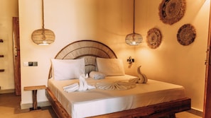 A neatly made bed with white linens, a wooden headboard, and a decorative swan pillow. - Jua Boutique Hotel (Jambiani)