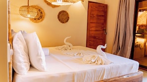 Una cama bien tendida con sábanas blancas y un diseño de toalla con forma de cisne.