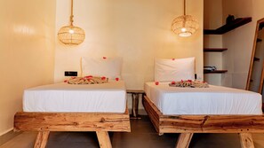 Two wooden beds with white linens and red flowers, a hanging light fixture, and a wooden bench. - Jua Boutique Hotel (Jambiani)