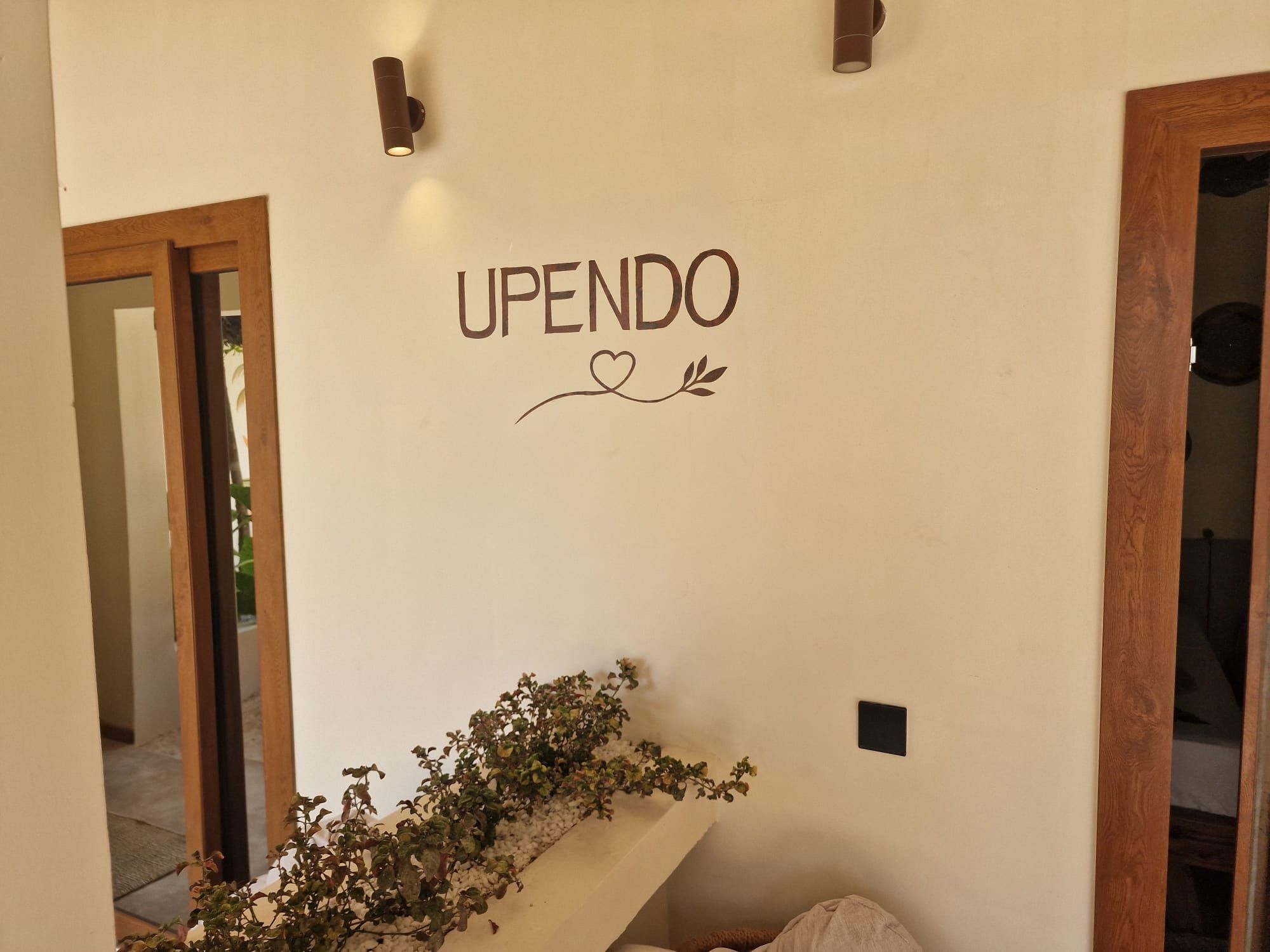 Una pared con la palabra 'UPENDO' y un diseño decorativo de corazón y hoja.