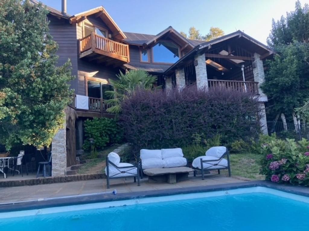 Una casa de dos pisos con balcón, piscina y mobiliario exterior.