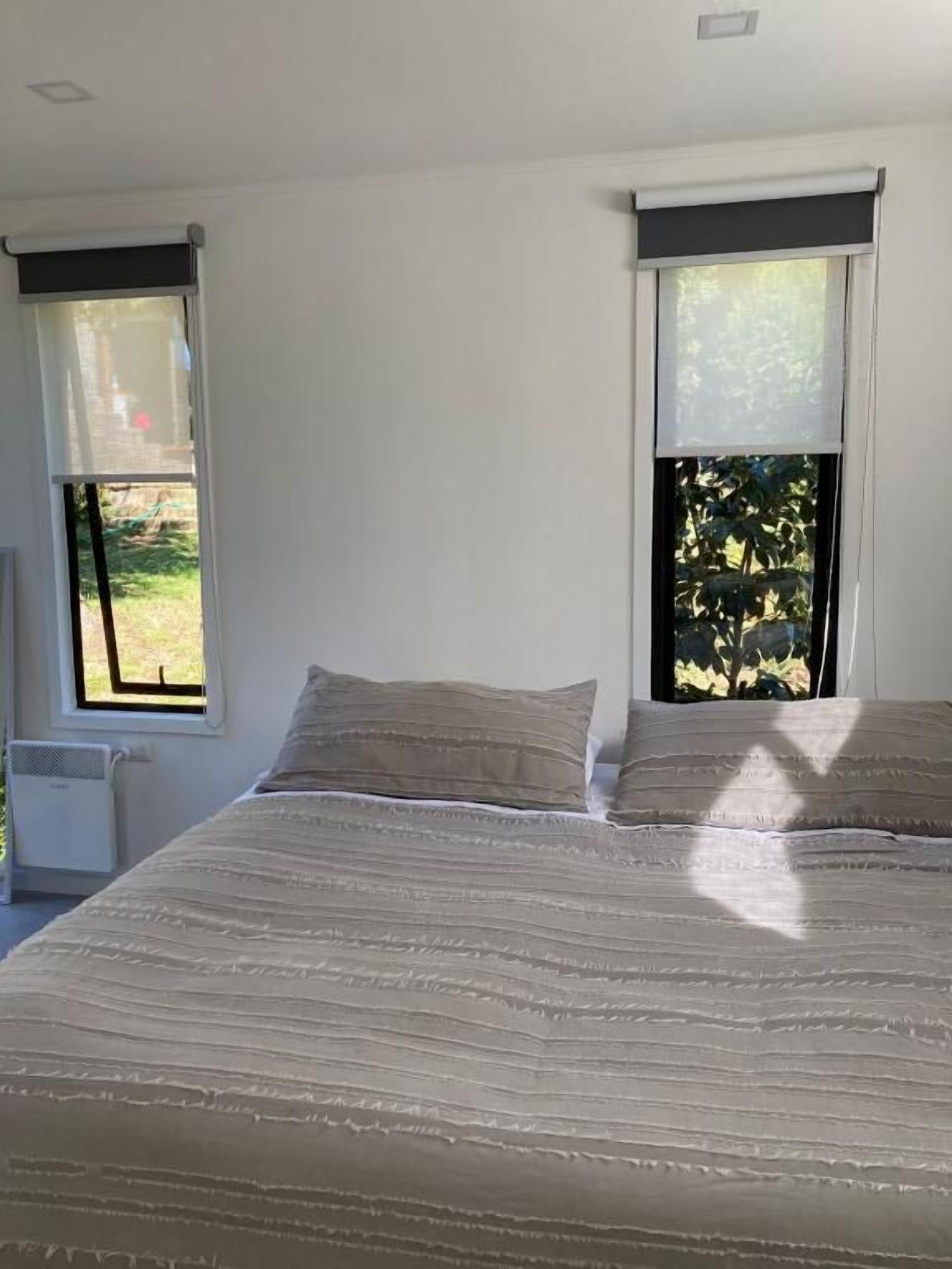 A bedroom with a bed, two windows, and a radiator.