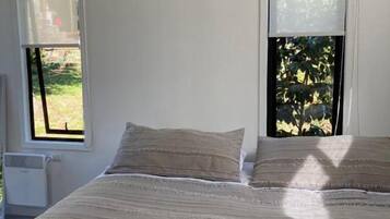A bedroom with a bed, two windows, and a radiator.