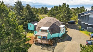 Une petite maison de plain-pied, dotée d’un toit en pente, d’une terrasse en bois et d’une allée gravillonnée.
