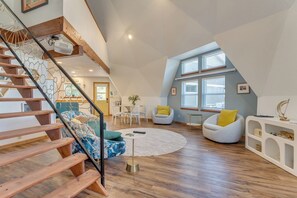 Un loft spacieux avec un escalier en bois, une table basse ronde et un coin salon avec des fauteuils.