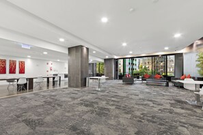 A modern office space with a large open area, seating arrangements, and a view of the cityscape through large windows. - CBD Sanctuary | 2BR, Tram, Pool, Spa, Sauna & Gym (Melbourne)