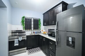 Una cocina moderna con electrodomésticos de acero inoxidable, armarios negros y una ventana con vistas.