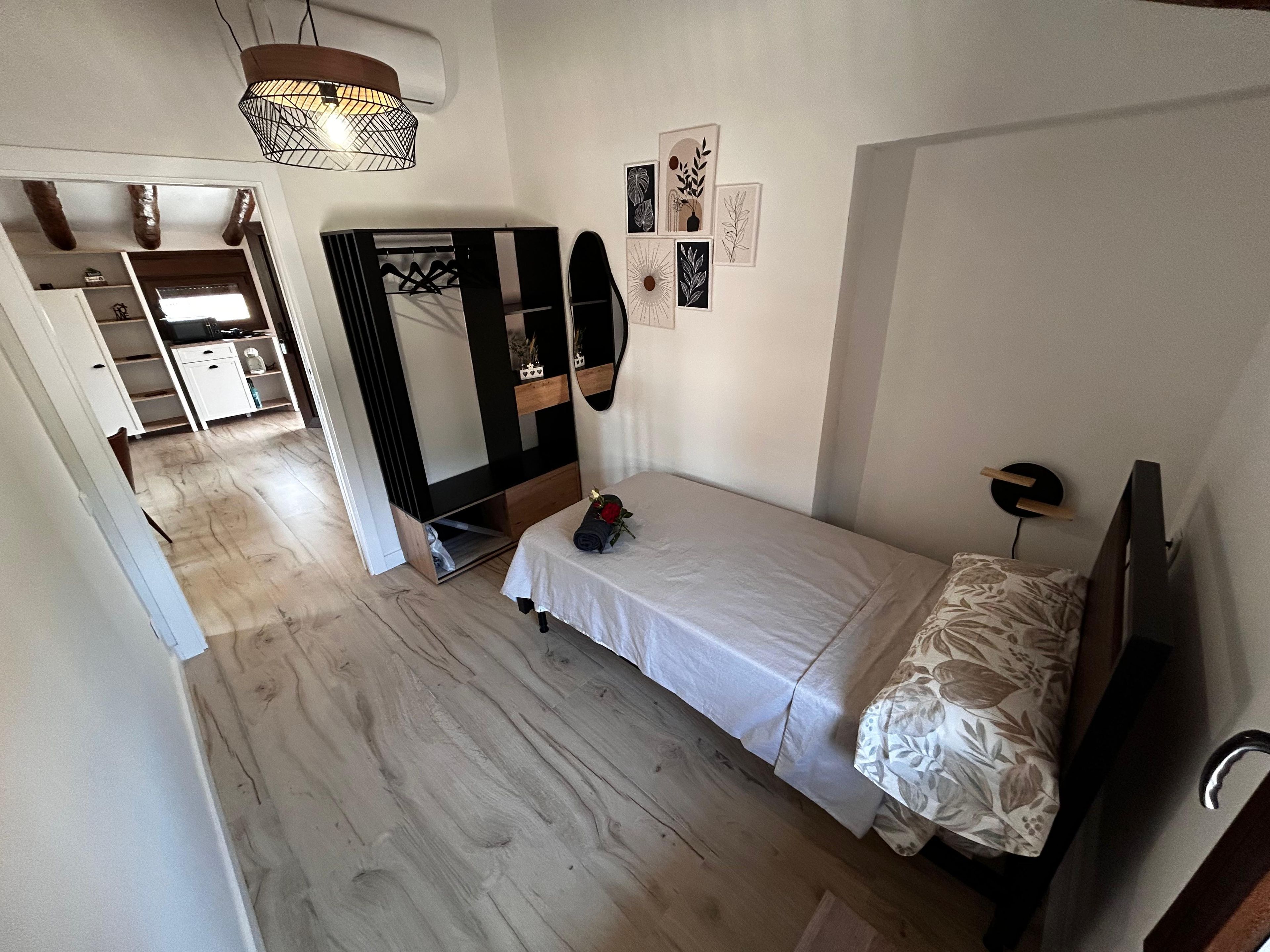 Een slaapkamer met een bed, een spiegel, een kledingkast en een aan de muur bevestigde televisie.