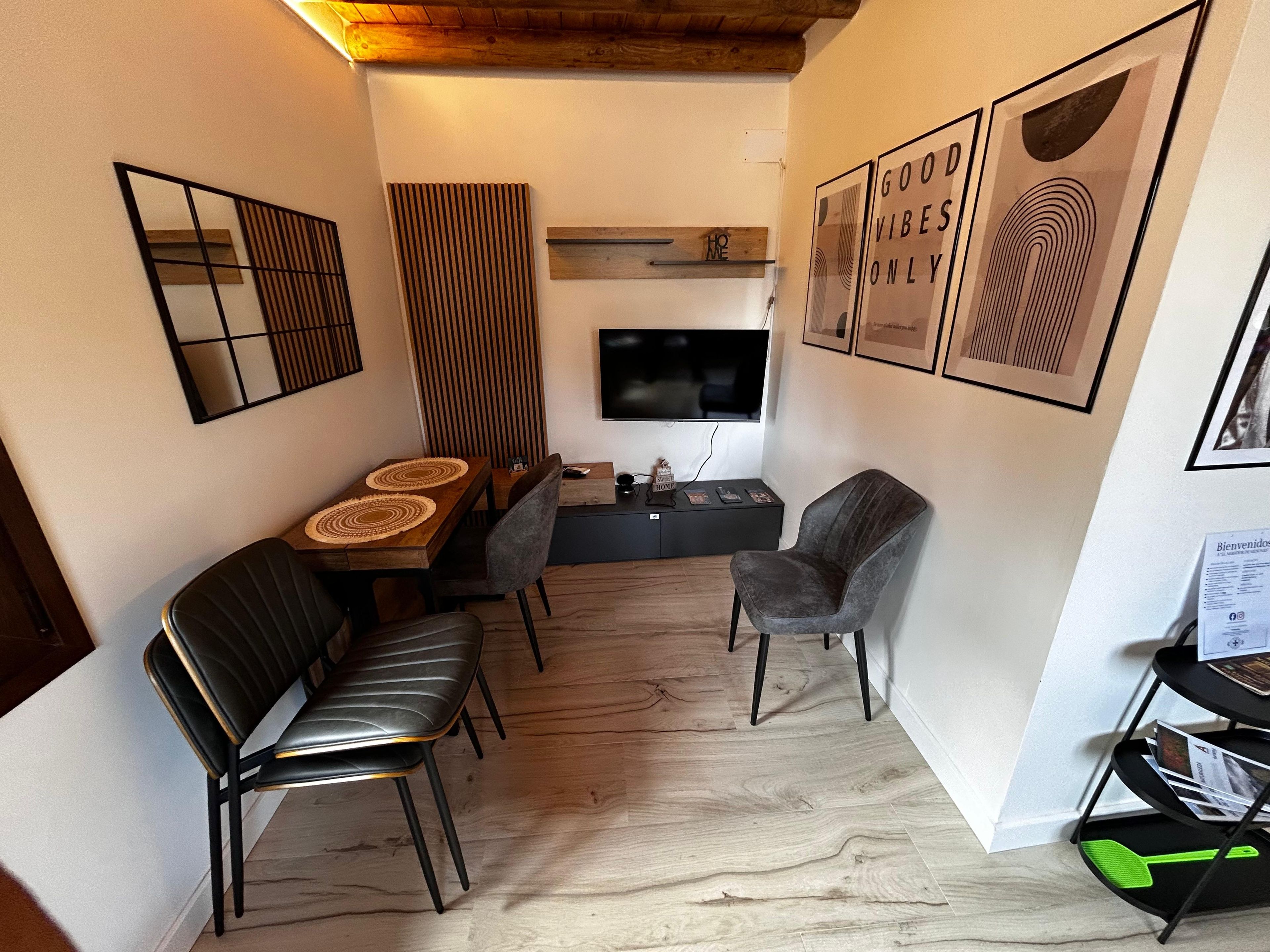 Um espaço compacto com área de refeições, assentos, TV de tela plana e obras de arte nas paredes.