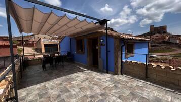 A patio area with a table and chairs, a covered seating area, and a view of the surrounding neighborhood.