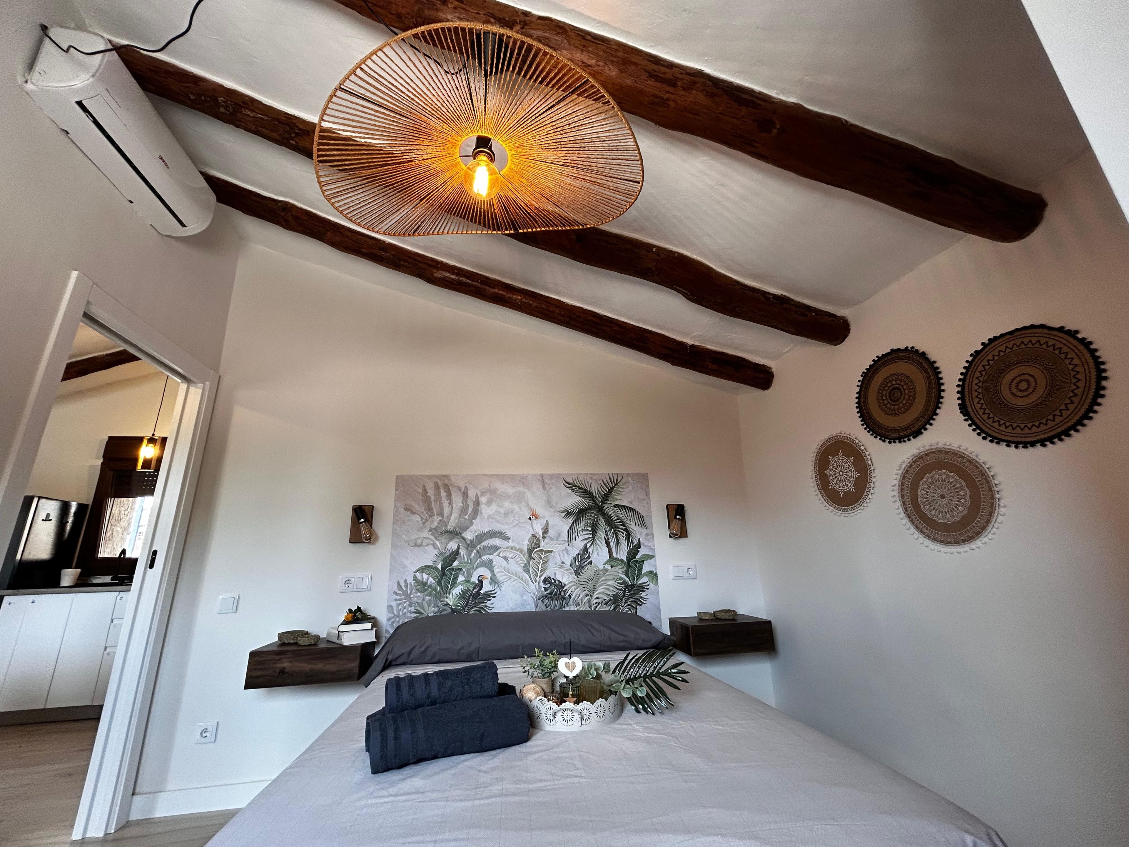 A bedroom with a bed, a wall-mounted light fixture, a painting, and decorative wall plates.