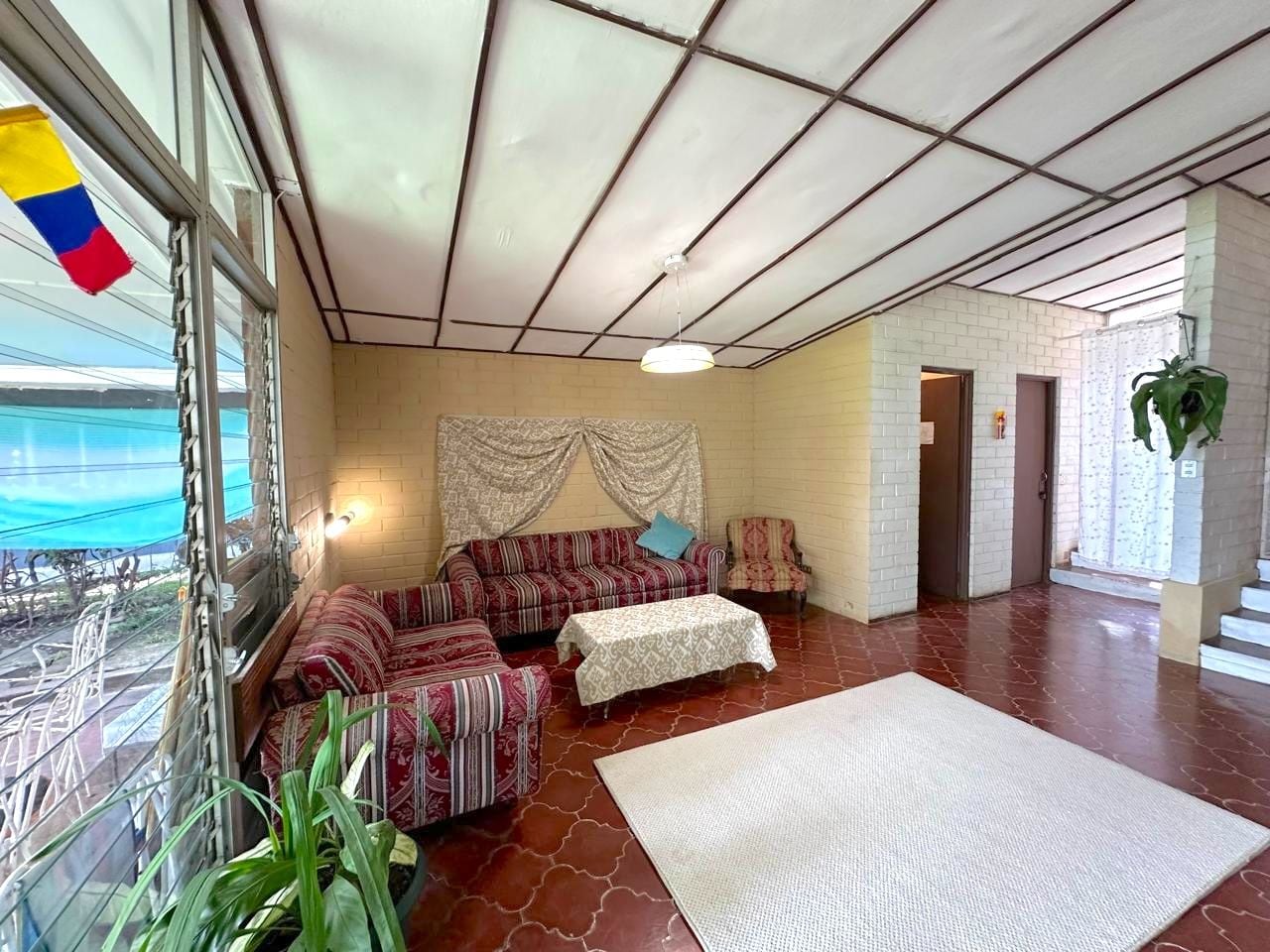 A spacious living area with a sofa set, a table, and a large window offering a view.