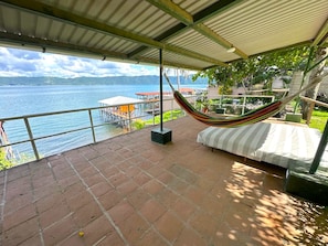 A covered terrace with a hammock, a view of the water, and a dining area. - Quaint 3-bedroom house in Santa Ana for a relaxing stay (Santa Ana)