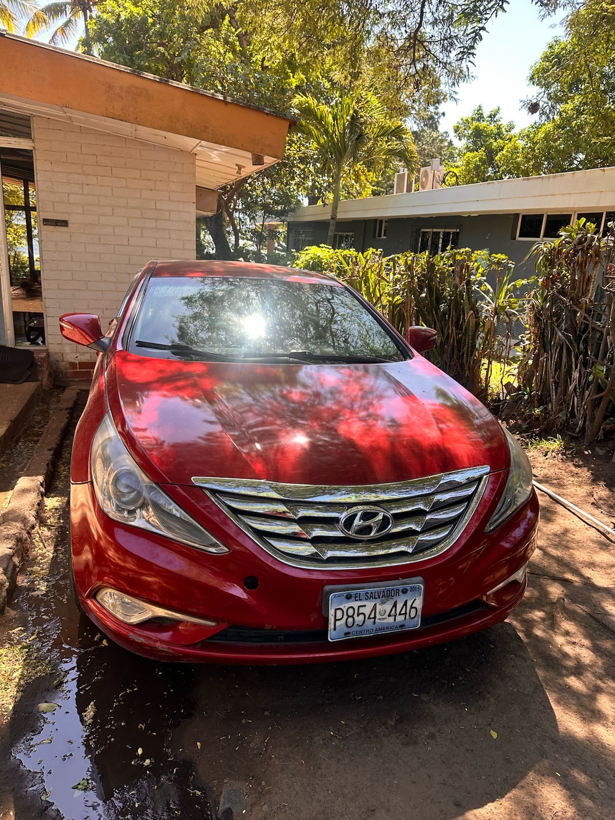 Une voiture rouge est garée devant un immeuble à la façade en briques.