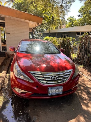 Un auto rojo estacionado frente a un edificio de fachada de ladrillo.