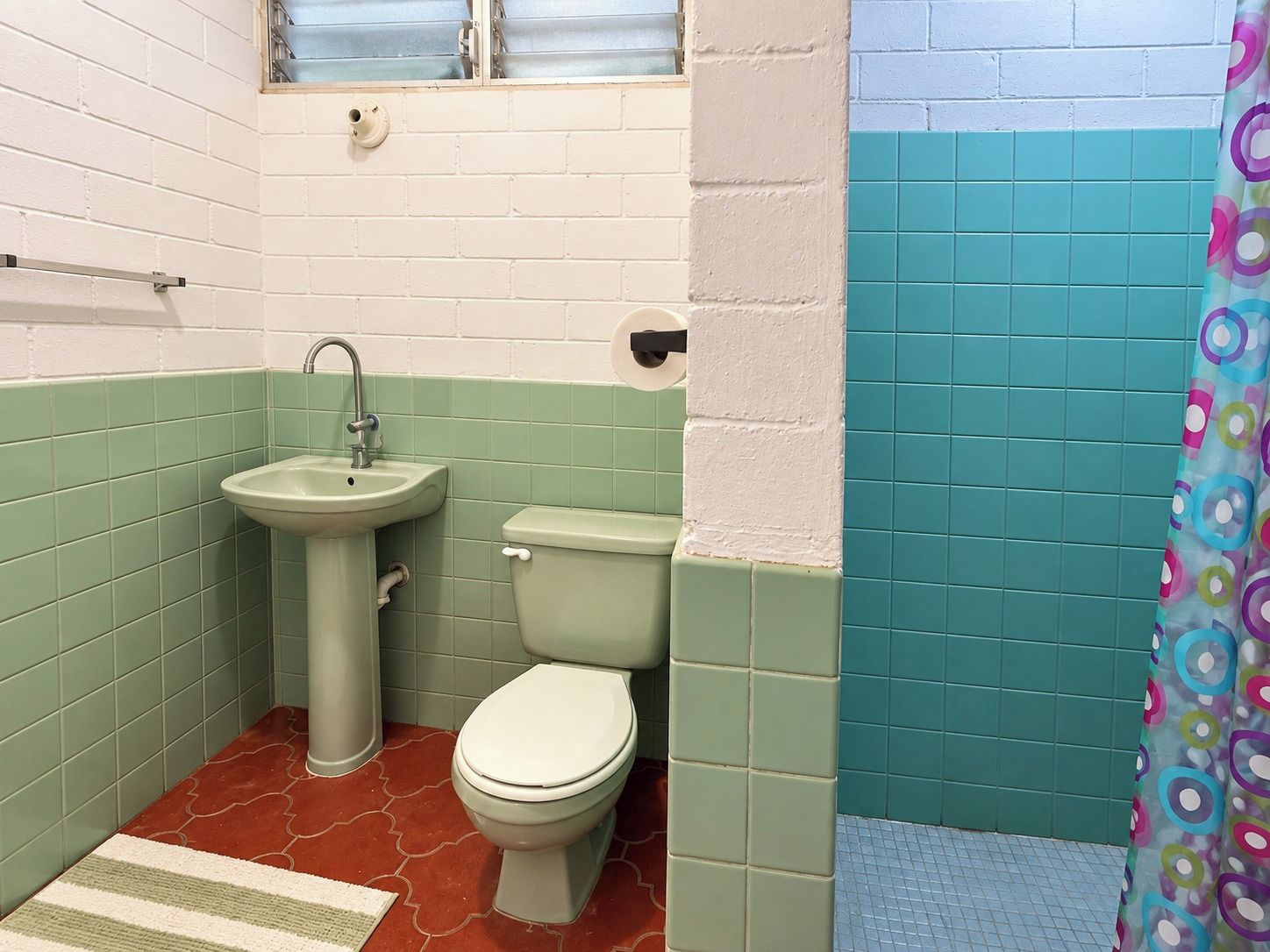 Une salle de bain avec un lavabo, des toilettes et un rideau de douche.