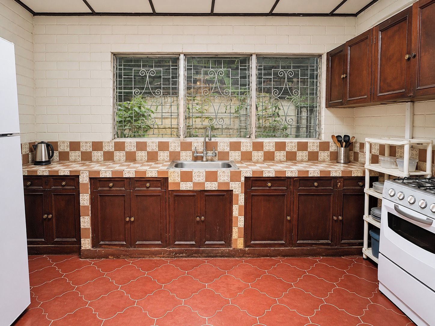 A kitchen with a checkered backsplash, a window with metal bars, wooden cabinets, a sink, and a stove.