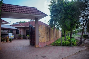 Una propiedad residencial con entrada pavimentada, acceso por portón y zona de estacionamiento techada.