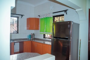 Una cocina con armarios de madera, un refrigerador de acero inoxidable y un ventanal con herrajes decorativos.