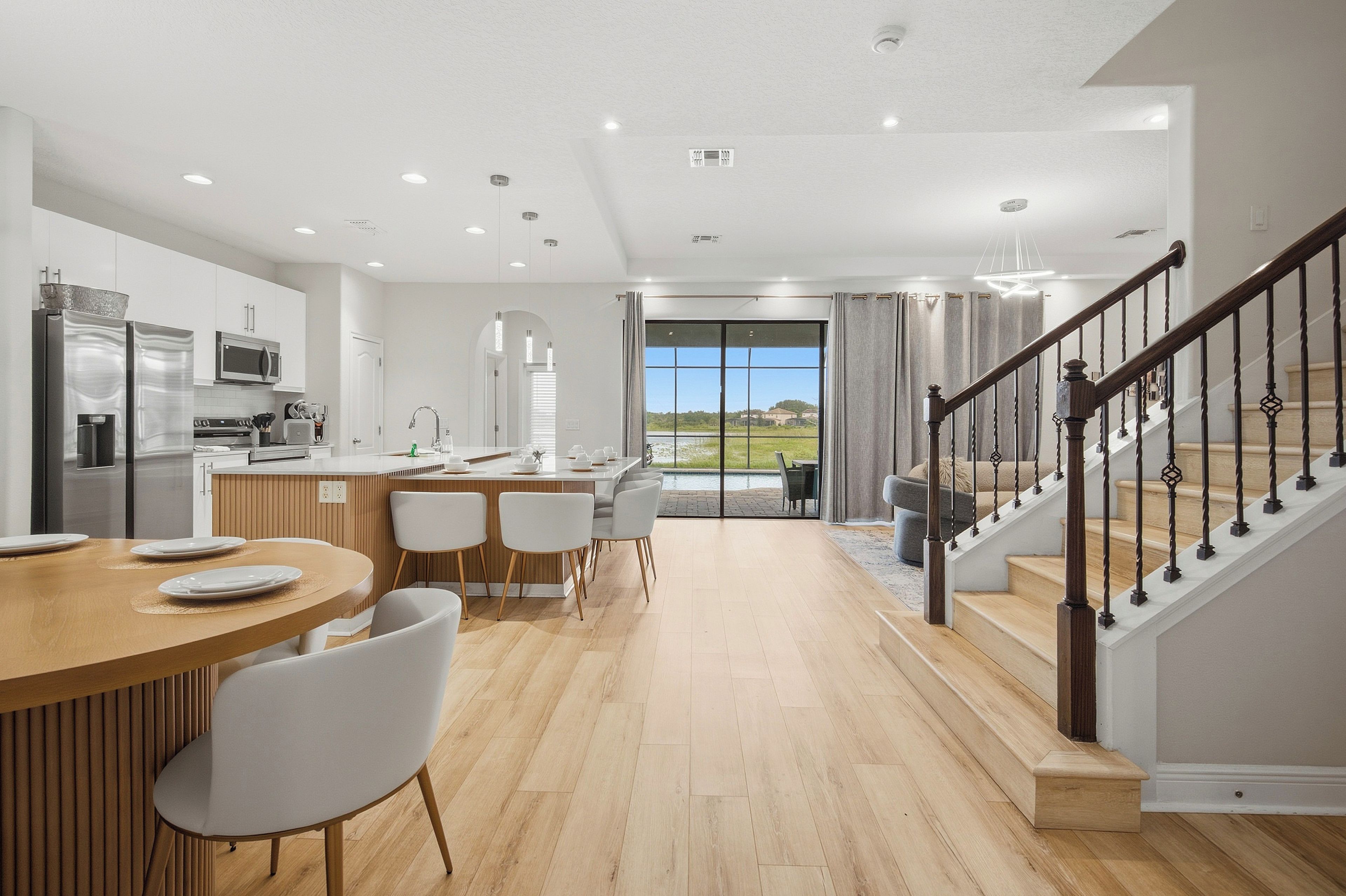 Une cuisine moderne avec un coin repas, un escalier et une vue sur l’extérieur.