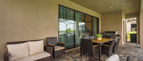 Ein Außenbereich mit Patio, Korbmöbeln, einem Holztisch und einem Grill.