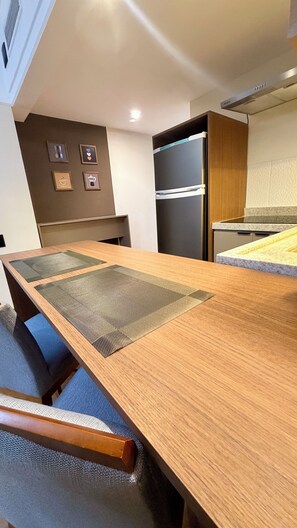 Eine moderne Küche mit einem Holztisch, Stühlen und einem Einbaukühlschrank.