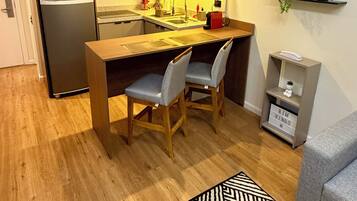 A compact kitchen with a refrigerator, a microwave, and a sink. There are two chairs and a small table.