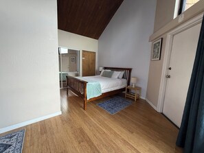 Ein Schlafzimmer mit einem hölzernen Bett, einem Nachttisch, einer Tür und einem Fenster.