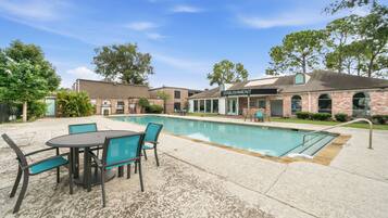 A pool area with a table and chairs, a building labeled 'ESTABLISHMENT,' and a clear sky.