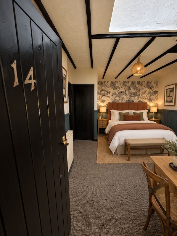 Un dormitorio con cama, mesitas de noche, escritorio y silla.
