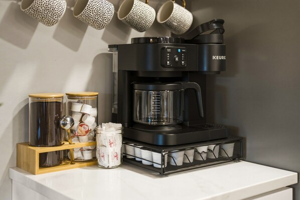A coffee machine with a digital display, a coffee grinder, and various coffee pods and containers on a countertop. - Hot Tub • Sauna • Fire Pit • Shawnee Forest (Elizabethtown)