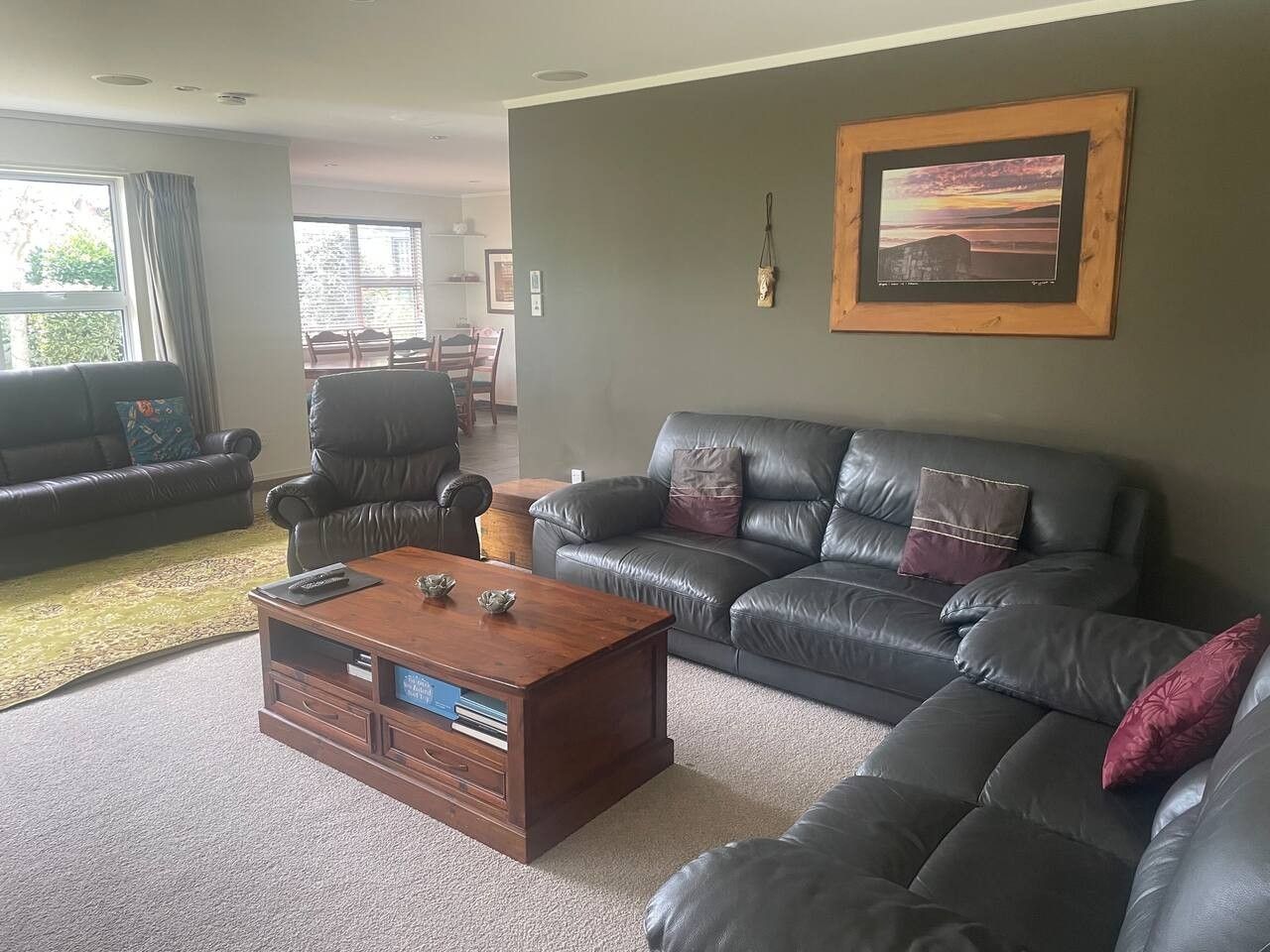 A living room with a leather sofa, a wooden coffee table, and a framed picture on the wall.