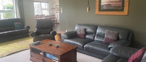 A living room with a leather sofa, a wooden coffee table, and a framed picture on the wall.