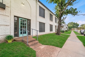 A two-story residential building with a green door, a small front yard, and a sidewalk. - Chic 2BR Apt in Houston (Houston)