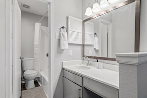 A bathroom with a toilet, sink, and mirror. - Chic 2BR Apt in Houston (Houston)