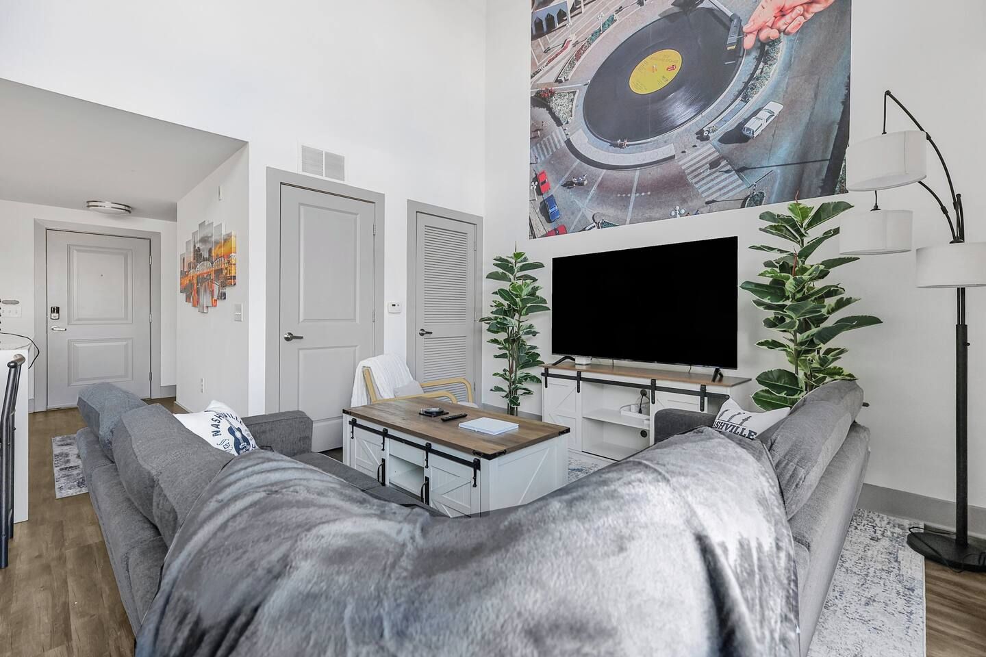 A modern living room with a sofa, a coffee table, a TV, and a plant.