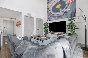 Ein modernes Wohnzimmer mit einer Couch, einem Couchtisch, einem Fernseher und einer Pflanze.