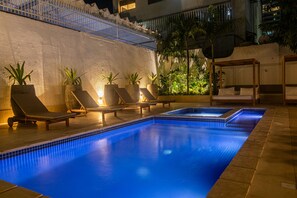 Una piscina con sillones de descanso y plantas en macetas.