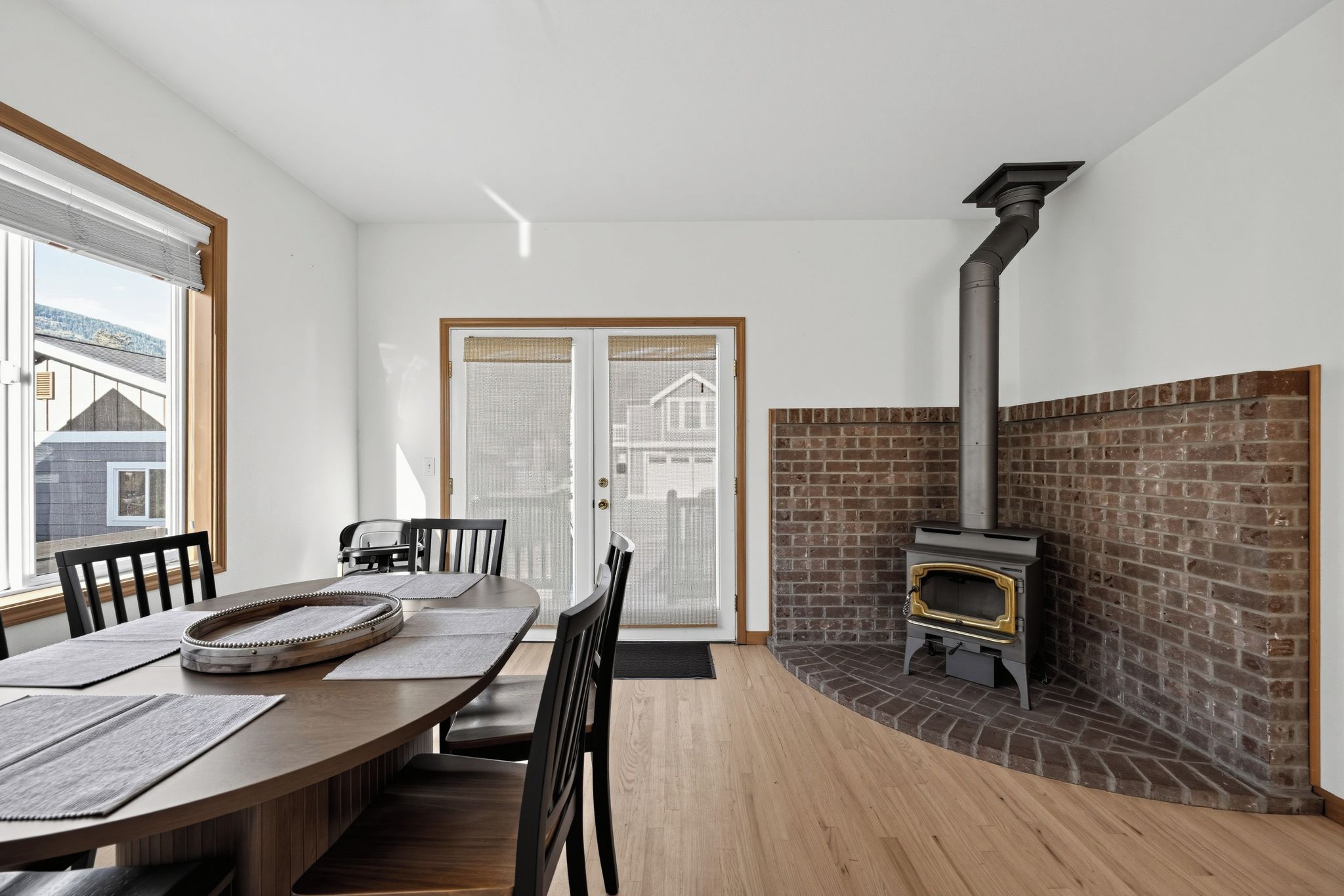 A dining area with a wooden table, chairs, and a brick fireplace.