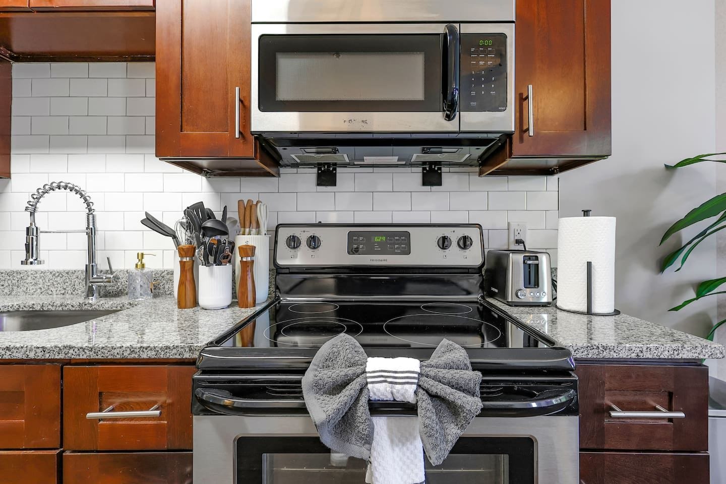 A kitchen with a stainless steel microwave, a stove, and a sink.