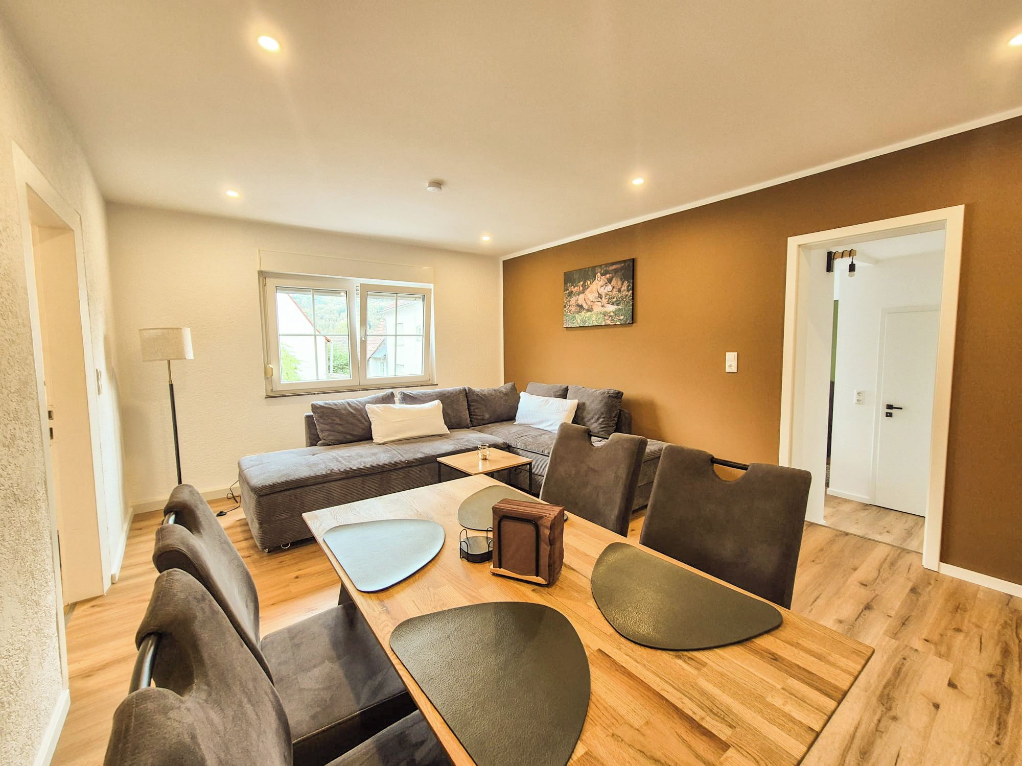 Un salon moderne avec un canapé, des fauteuils, une table basse et un tableau accroché au mur.