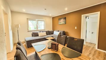 Un salon moderne avec un canapé, des fauteuils, une table basse et un tableau accroché au mur.